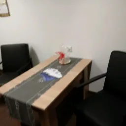 Stół z bieżnikiem i dekoracją w biurze w Lublinie, otoczony dwoma czarnymi krzesłami, przy ścianie w jasnym odcieniu.