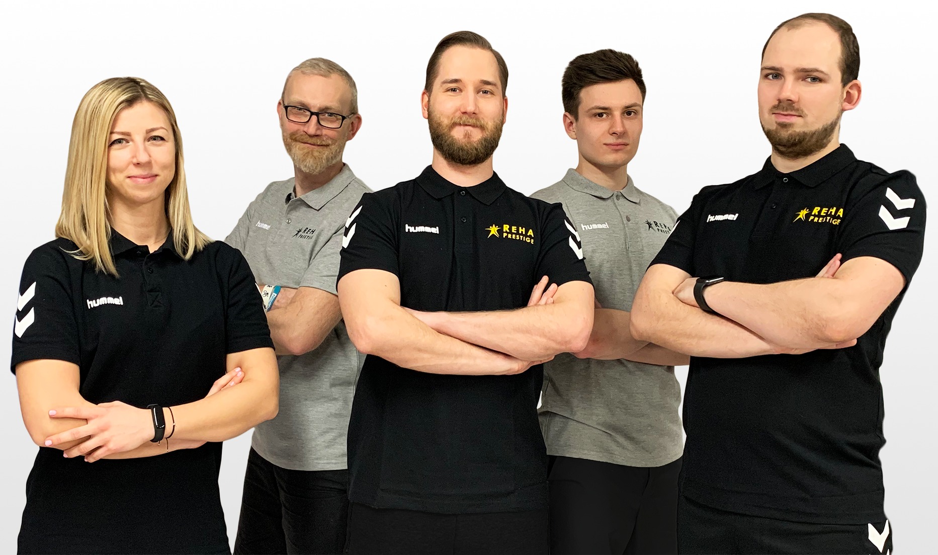 Grupa pięciu fizjoterapeutów i rehabilitantów w firmowych koszulkach polo z logo Reha Prestige, stojących na jasnym tle z założonymi rękami.