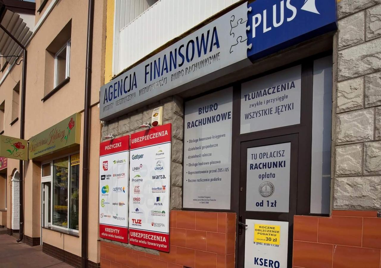 Fasada budynku z szyldami: Agencja Finansowa, Biuro Rachunkowe, Tłumaczenia zwykłe i przysięgłe wszystkich języków, reklamy pożyczek i ubezpieczeń różnych firm, oraz informacja o opłacie rachunków...