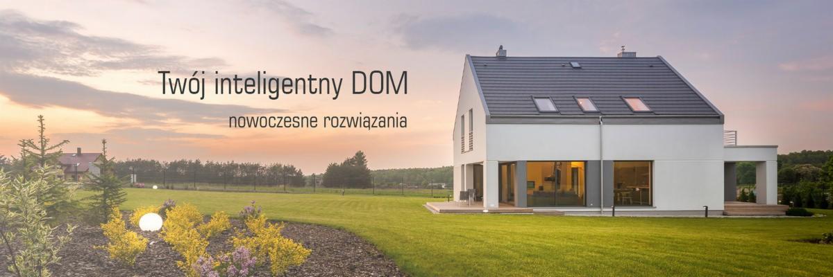Nowoczesny, biały dom z szarą dachówką i trzema oknami dachowymi, oświetlony ciepłym światłem zachodzącego słońca, otoczony zadbanym trawnikiem i ozdobnymi krzewami z kulistymi lampami ogrodowymi.