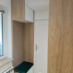 Meble na Wymiar DOMEB Łukasz Pamuła - Funkcjonalna zabudowa wnęki z siedziskiem i szafką wiszącą, wykończona drewnopodobną okleiną. Obok białe drzwi i fragment grzejnika.