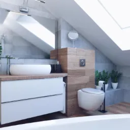 Nowoczesna łazienka na poddaszu z oknem dachowym, szare płytki, biała umywalka nablatowa i toaleta podwieszana, drewniane akcenty i rośliny doniczkowe.