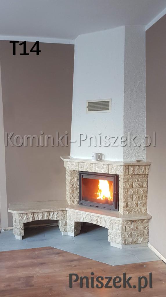 Wykończony, narożny palenisko obłożone jasnym kamieniem, z płonącym ogniem, przylegające do niego siedzisko, biała obudowa z kratką wentylacyjną, na obudowie stoi biały kubek.