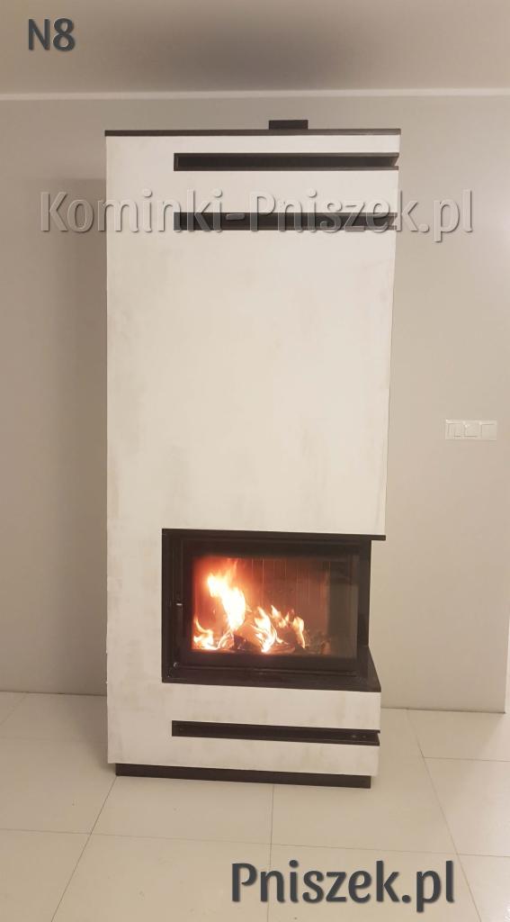 Nowoczesny, biały piec wolnostojący z czarnymi akcentami, z palącym się wewnątrz ogniem, na tle jasnej ściany i podłogi. Widoczne logo firmy na górze i dole zdjęcia.