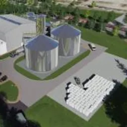 Wizualizacja z lotu ptaka przedstawiająca kompleks budynków przemysłowych z dwoma dużymi silosami, magazynem, zaparkowanymi samochodami i stertą białych bel, otoczony zielenią.