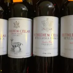 Butelki wina z etykietami Bethlehem Cellar, w tym Chenin Blanc z rysunkiem antylopy, ustawione w rzędzie, widoczne roczniki 2014 i logo Bread & Wine.