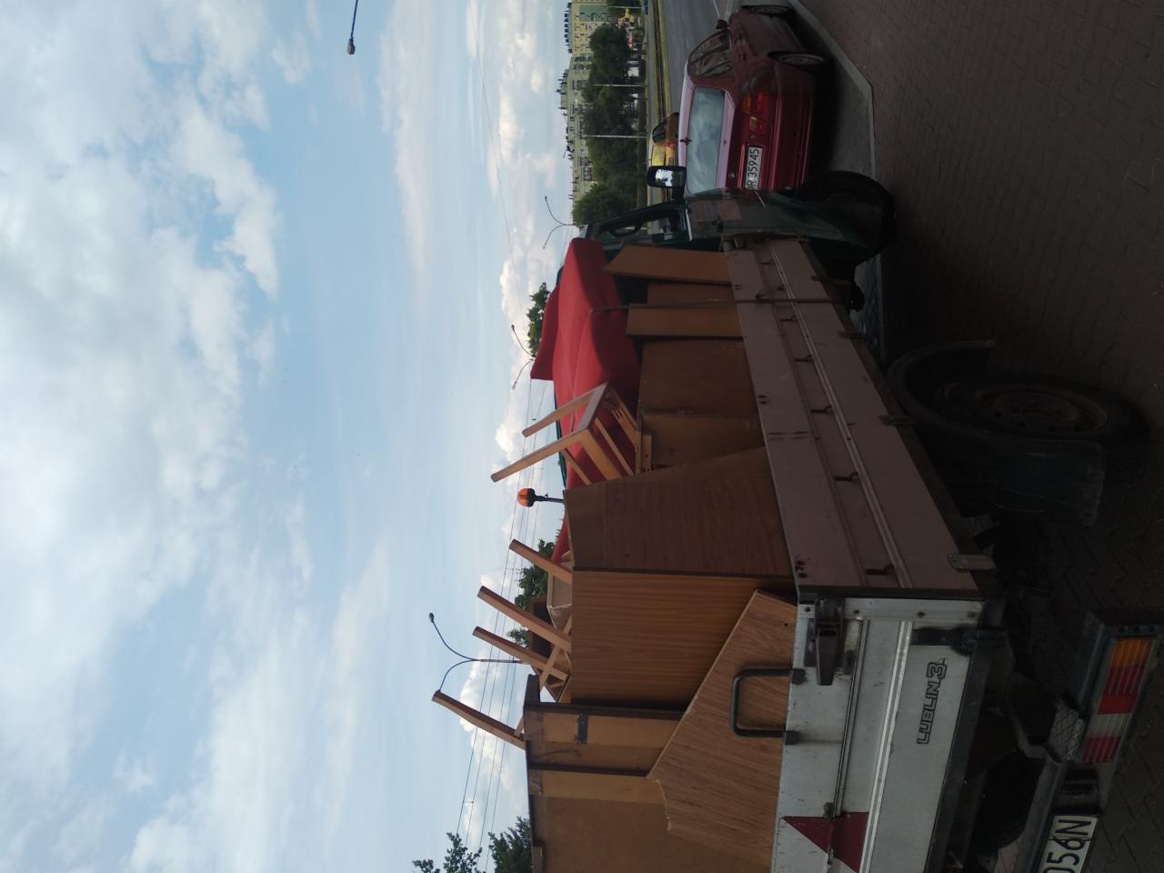 Napełniona skrzynia ładunkowa ciężarówki z meblami i elementami wyposażenia wnętrz podczas transportu, widok z dołu na tle błękitnego nieba.