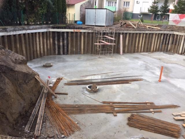 Wykonany wykop zabezpieczony ścianką berlińską, widoczne zbrojenia i studzienki kanalizacyjne na dnie wykopu.