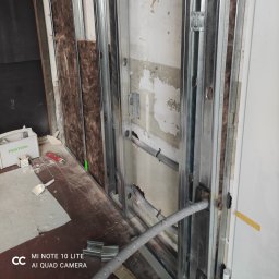 LUX&ART WNĘTRZA ŁUKASZ WĘGLOWSKI - Wnętrze w trakcie prac wykończeniowych: metalowy szkielet ściany z izolacją, widoczne kable i narzędzia. Przygotowanie do dalszych prac.