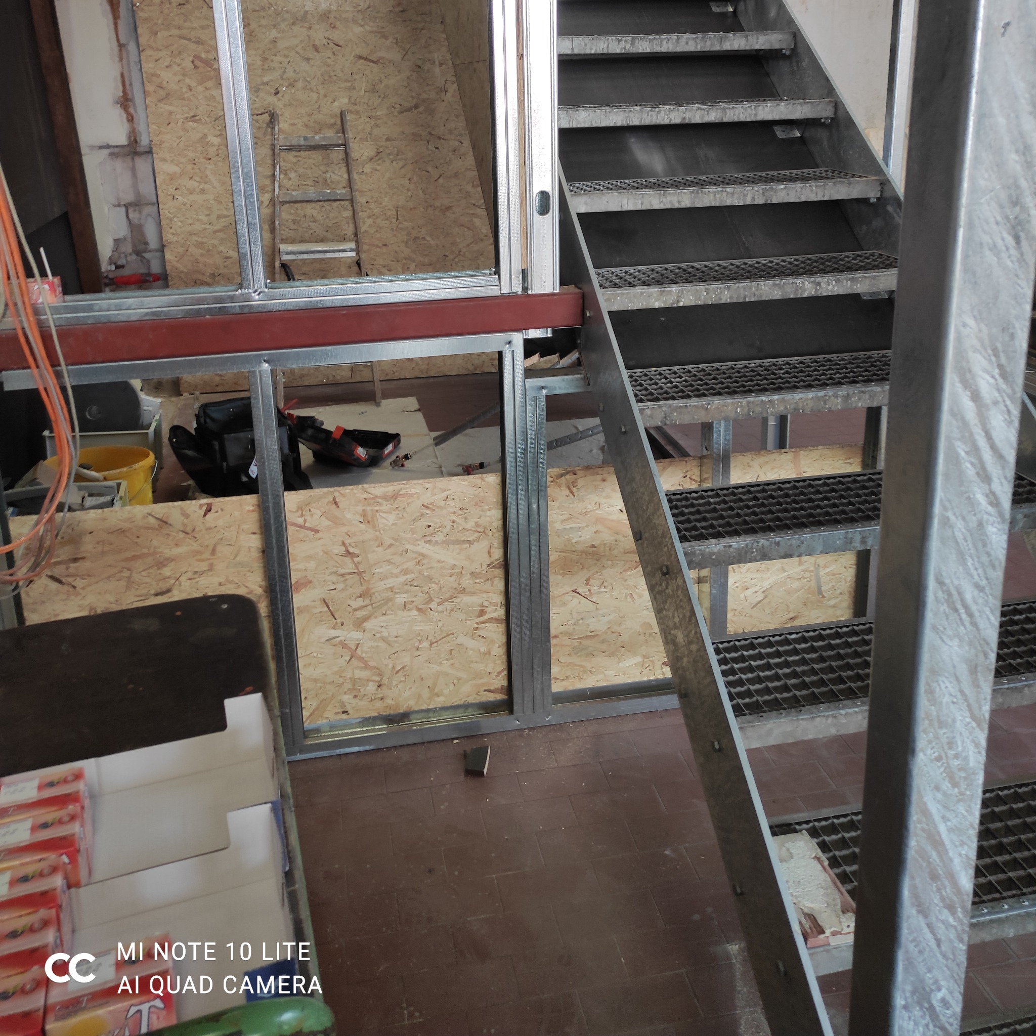 Montaż ścian działowych z płyt OSB i metalowych profili. Widoczna konstrukcja szkieletowa i metalowe schody. Etap prac wykończeniowych wnętrz.