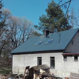 Normal-rembud Wojciech Rutkowski - Dom jednorodzinny z nowym, grafitowym dachem z blachy na rąbek stojący z trzema oknami dachowymi, widoczne pozostałości po starym dachu i gruz.
