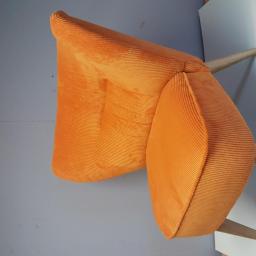 Meb-lokum - Pomarańczowe krzesło tapicerowane sztruksem, widoczne z góry, z drewnianymi nogami na tle szarej ściany.