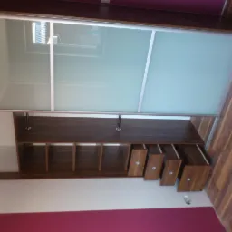 Wnętrze szafy wnękowej z przesuwnymi drzwiami z mlecznego szkła, widoczne półki i wysuwane szuflady z drewnianymi frontami i metalowymi uchwytami, wnętrze w odcieniach brązu i bieli, ściana...