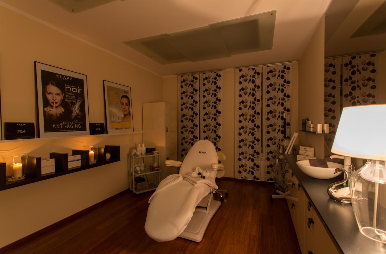 Przytulne wnętrze gabinetu z fotelem kosmetycznym marki Klapp, półkami z kosmetykami, świecami i dekoracyjnymi zasłonami w tle.