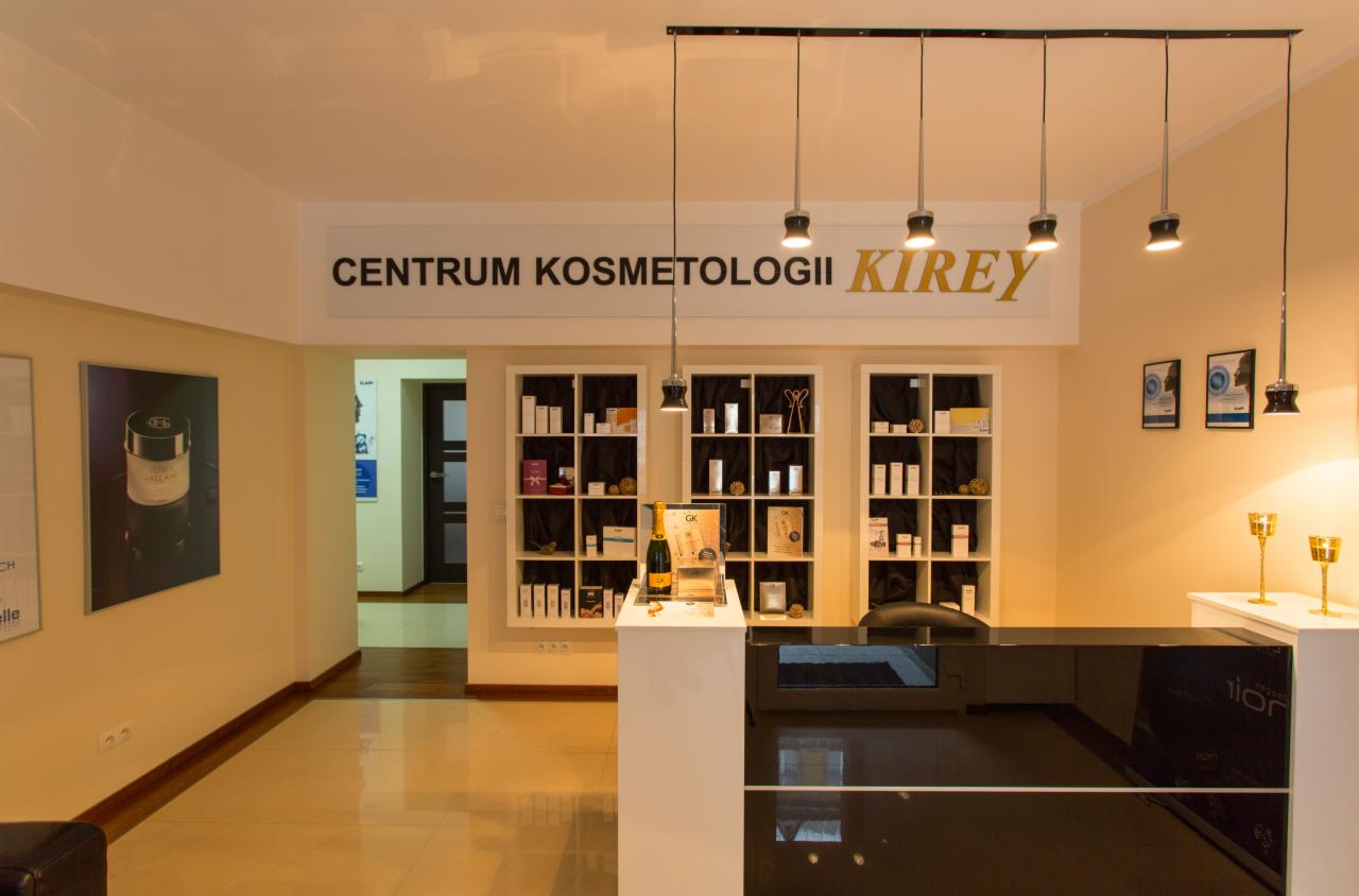 Recepcja w centrum kosmetycznym Kirey z czarnym błyszczącym blatem, ekspozycją produktów na półkach i dekoracyjnymi świecznikami.