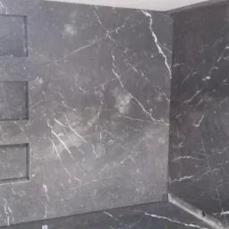 Wykończona ściana prysznicowa z czarnego kamienia z białymi żyłkami i trzema wnękami na kosmetyki.