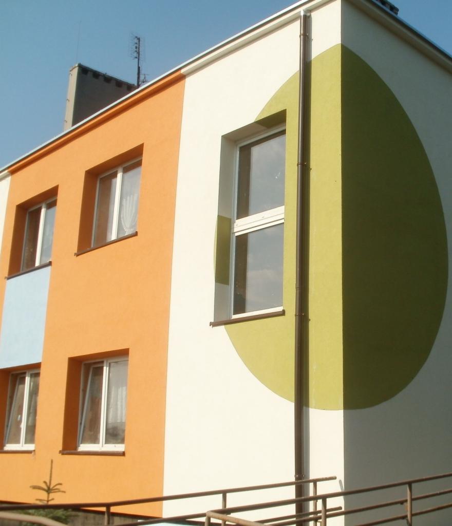 Elewacja budynku po remoncie w Dąbrowie Górniczej, z oknami i pomalowaną ścianą w geometryczne wzory: pomarańczowy, biały i zielony okrąg.