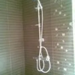 Wykończona kabina prysznicowa z chromowanym zestawem natryskowym na tle brązowych płytek z delikatnym wzorem.