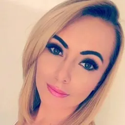 Portret kobiety z blond włosami i wyrazistym makijażem, uśmiechająca się do kamery.