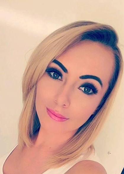 Portret kobiety z blond włosami i wyrazistym makijażem, uśmiechająca się do kamery.