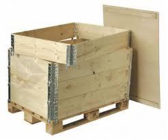 Drewniana skrzyniopaleta z metalowymi okuciami, częściowo złożona, obok leży płaska płyta, prawdopodobnie element zamykający.