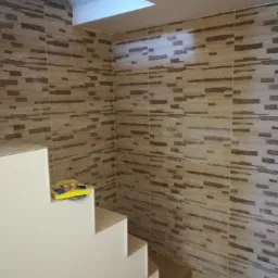 Wykończone schody z okładziną imitującą kamień na ścianach, na schodach leżą żółte gąbki