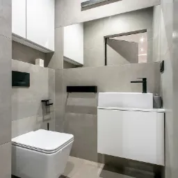 Nowoczesna łazienka w odcieniach szarości z podwieszaną toaletą, białą szafką z umywalką i dużym lustrem z oświetleniem LED.