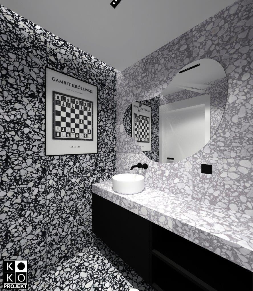 Nowoczesna łazienka w czarno-białej kolorystyce z umywalką nablatową, blatem z lastryko i lustrem w kształcie serca. Na ścianie plakat z motywem szachowym.