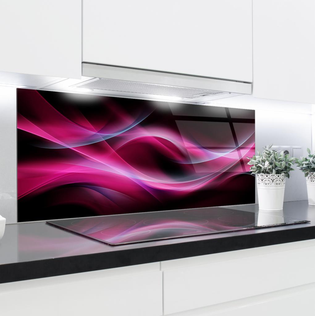 Szklany panel dekoracyjny z abstrakcyjnym motywem różowych i niebieskich fal zamontowany nad płytą indukcyjną w nowoczesnej kuchni z białymi szafkami.