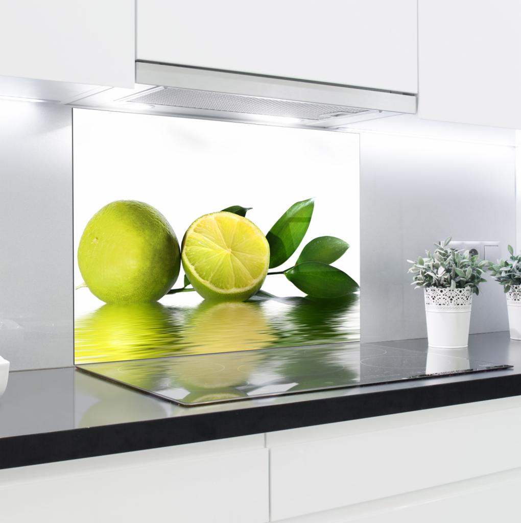 Szklany panel kuchenny z motywem limonki i odbiciem w wodzie, zamontowany nad płytą indukcyjną w nowoczesnej, białej kuchni.