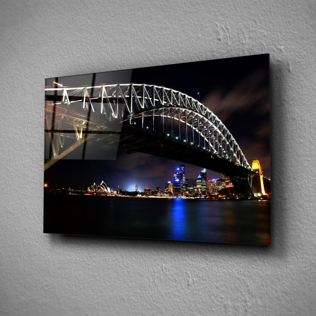 Szklany obraz przedstawiający nocny widok na most Harbour Bridge i Operę w Sydney, z widocznym odbiciem w tafli szkła.