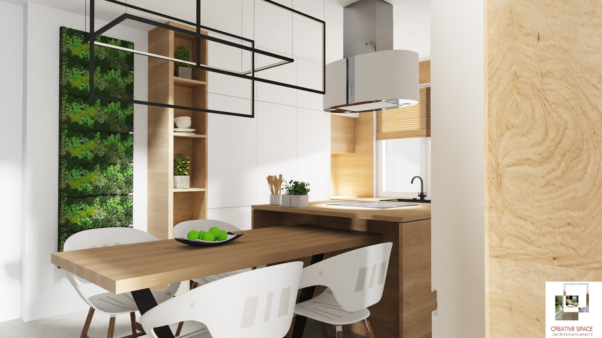 Nowoczesna kuchnia z drewnianym blatem, białymi szafkami i pionową zieloną ścianą z roślin. Na stole misa z zielonymi jabłkami, nad stołem geometryczna lampa. Widoczny fragment okna z żaluzjami...