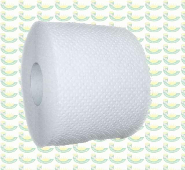 Rolka białej, perforowanej włókniny na tle wzorzystej tapety.