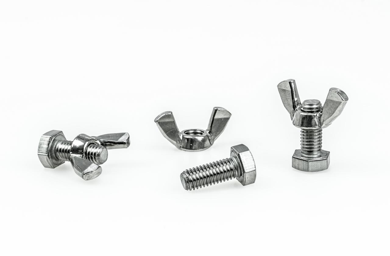 Cztery metalowe śruby i nakrętki motylkowe na białym tle, z widocznymi gwintami i sześciokątnymi łbami.