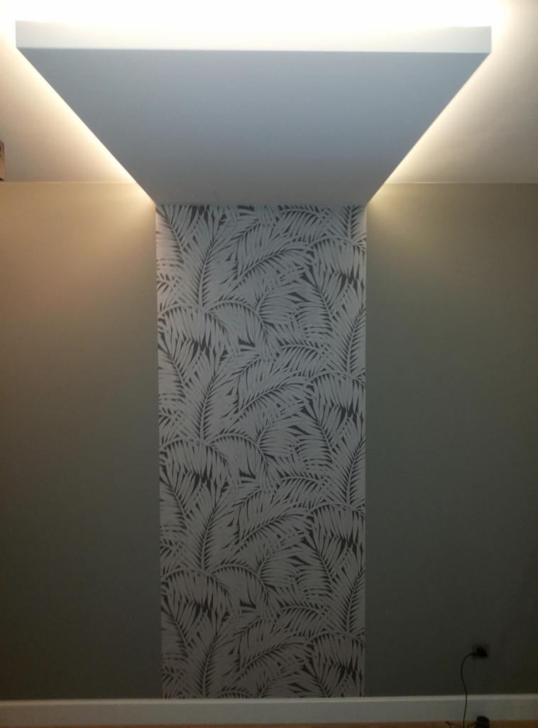 Wnęka z tapetą w liście palmowe, podświetlona listwą LED w suficie podwieszanym, ściany pomalowane na szaro.