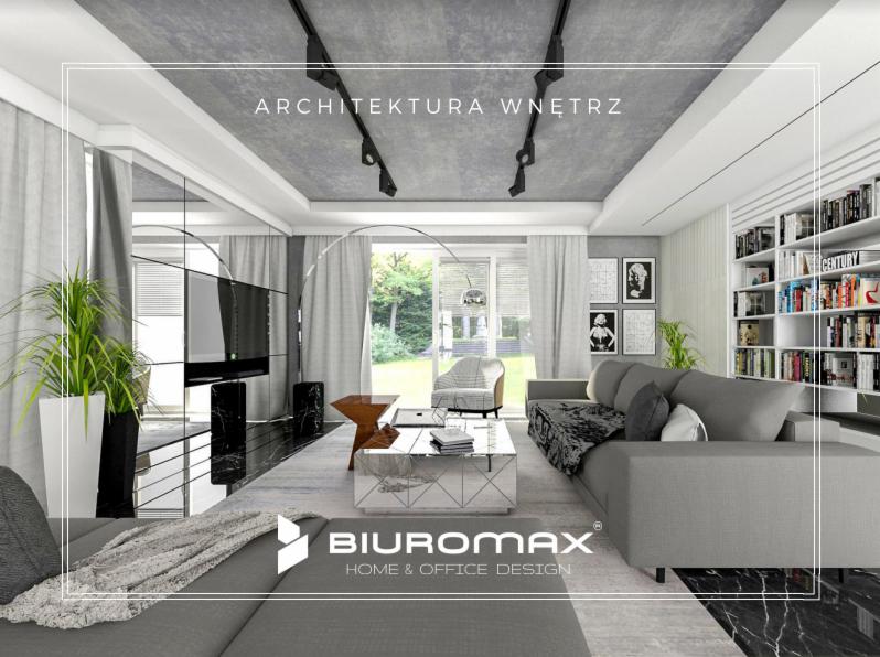 Salon w szarościach z marmurową podłogą, szary narożnik z narzutą, biały regał z książkami, betonowy sufit z reflektorami i logo firmy Biuromax w dolnej części zdjęcia.