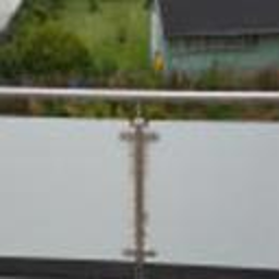 PHU Ślęża - Szklana balustrada balkonu z nierdzewnymi elementami mocującymi i widokiem na zieleń w tle.