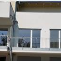 PHU Ślęża - Nowoczesny budynek z balkonami zabezpieczonymi metalowymi balustradami, widok z zewnątrz, okna z roletami zewnętrznymi.