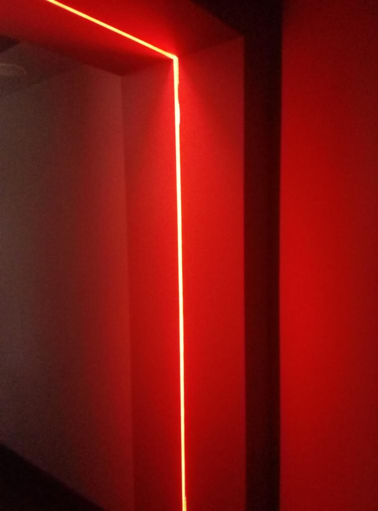 Wnętrze w Piasecznie z podświetleniem LED wzdłuż krawędzi ściany, tworzące pionową linię świetlną.