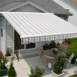 Rozkładana markiza nad patio z meblami ogrodowymi i kwiatami w donicach, widok z góry.