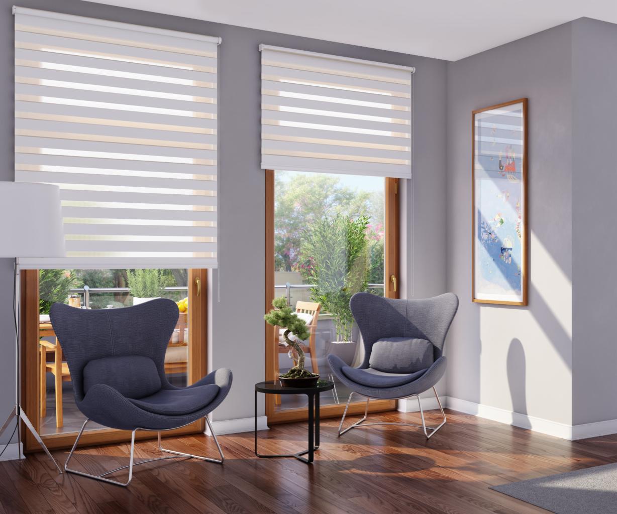 Nowoczesne rolety dzień-noc w szaro-beżowej kolorystyce, zamontowane w oknach salonu z drewnianą podłogą i szarymi ścianami, oświetlone popołudniowym słońcem.