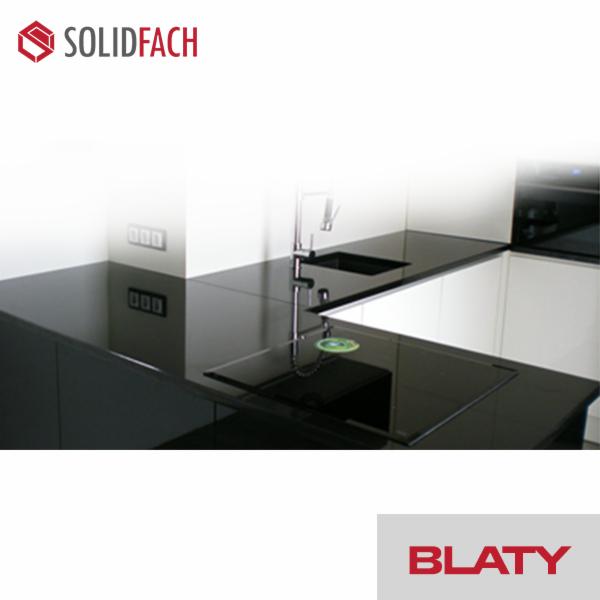 Nowoczesna kuchnia z czarnymi, lśniącymi blatami i minimalistycznym wystrojem, widoczne logo firmy Solidfach w lewym górnym rogu.