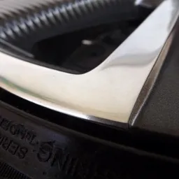 Detail of a car wheel with a polished silver rim and a tire showing the manufacturer's markings.