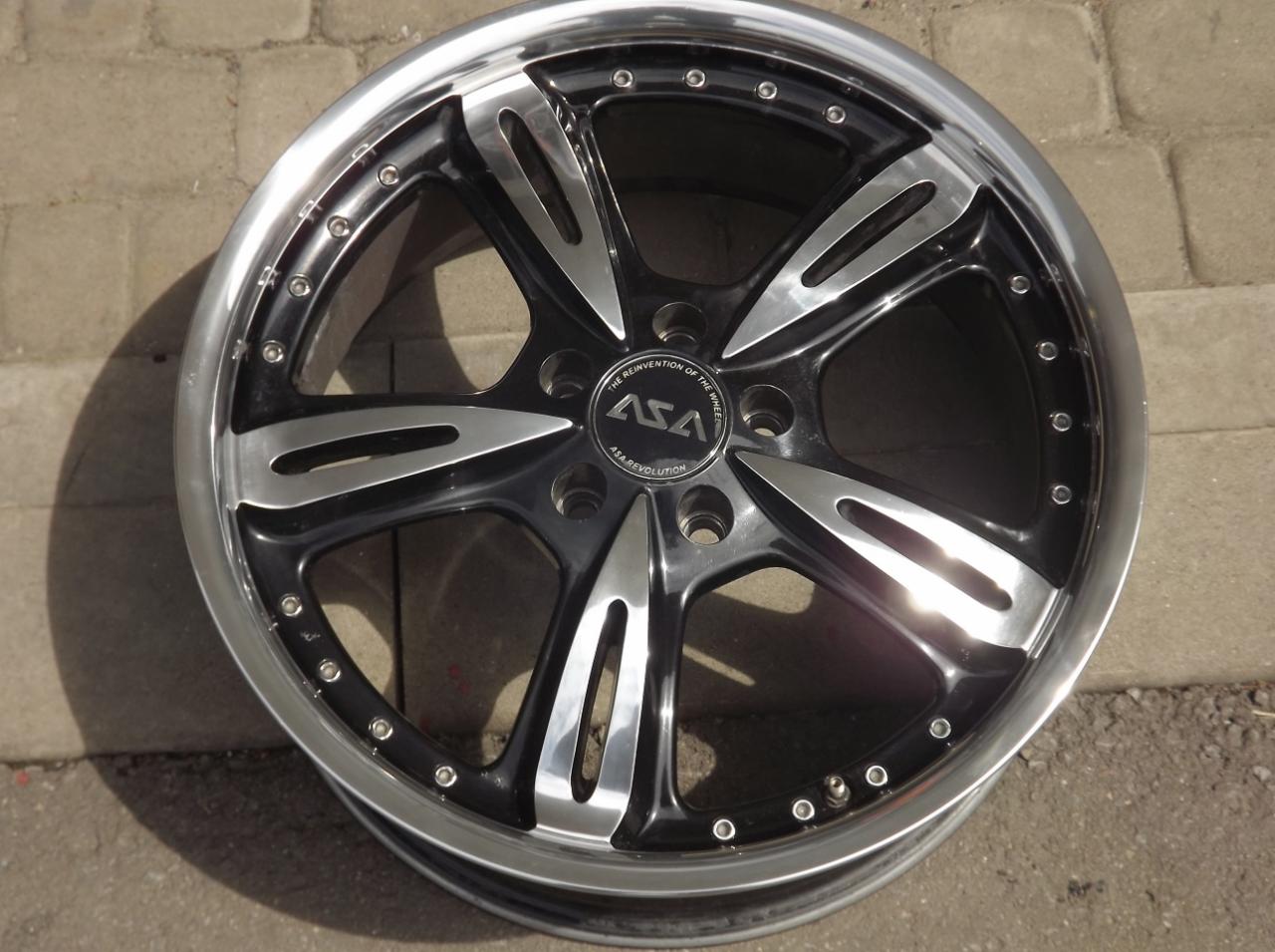Felga samochodowa ASA z pięcioma srebrnymi ramionami na tle kostki brukowej, widoczne ślady użytkowania.