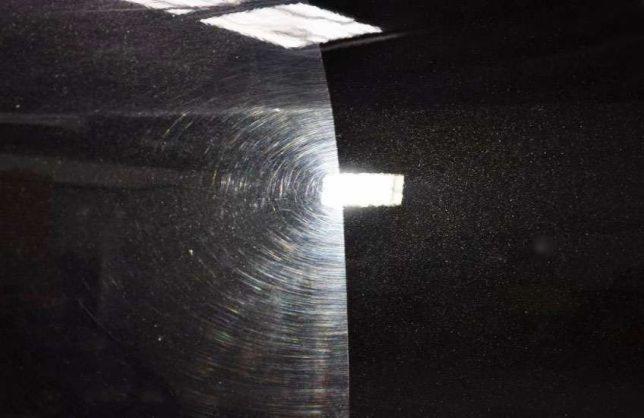 Część karoserii czarnego samochodu w Krosno, po lewej stronie widoczne koliste ślady polerowania, po prawej stronie powierzchnia przed polerowaniem.