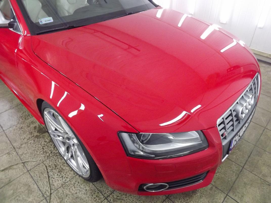Błyszczący, czerwony samochód sportowy Audi S5 po polerowaniu lakieru, widoczne odbicia światła na karoserii, chromowana atrapa chłodnicy i aluminiowe felgi.
