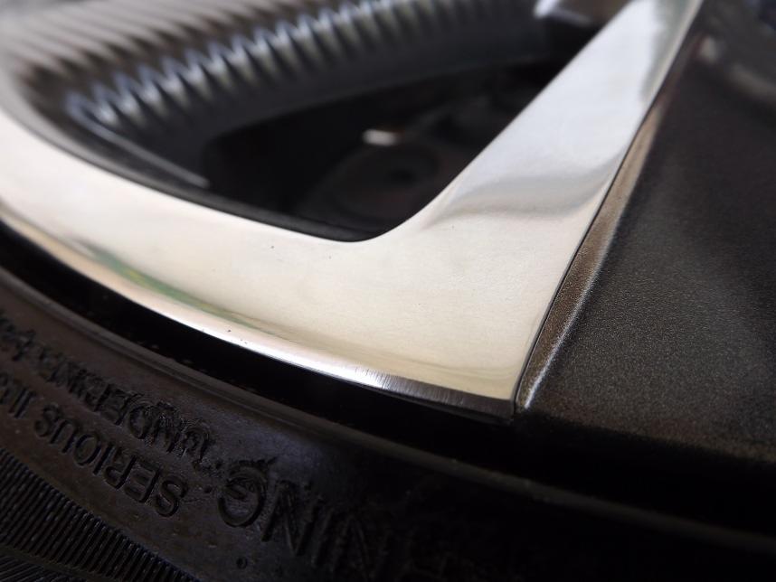 Detail of a car wheel with a polished silver rim and a tire showing the manufacturer's markings.