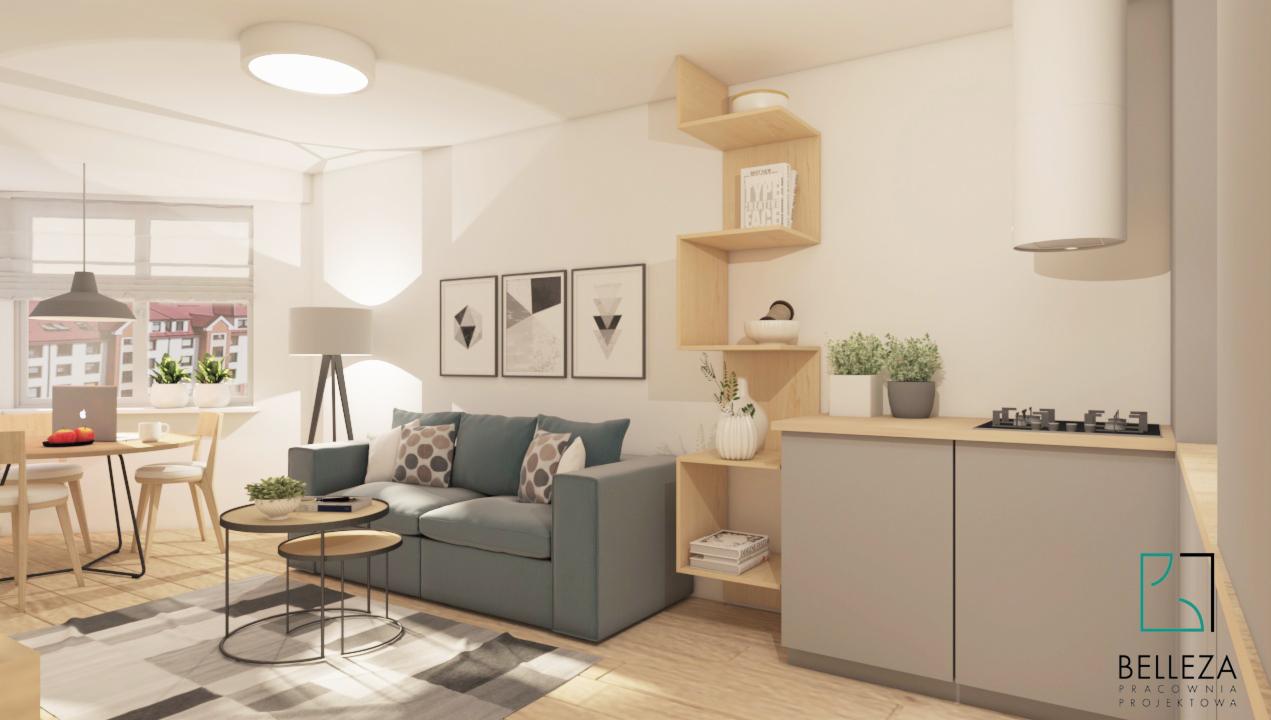 Wizualizacja salonu z aneksem kuchennym w jasnych barwach, z szarą sofą, drewnianymi półkami schodkowymi i okrągłym stołem z laptopem przy oknie.