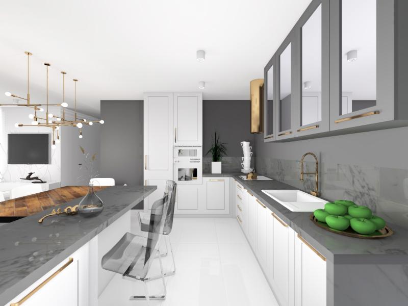 Nowoczesna kuchnia z białymi szafkami, szarym blatem z marmurowym wzorem, złotymi akcentami i przezroczystymi krzesłami barowymi. Na blacie leżą zielone jabłka.
