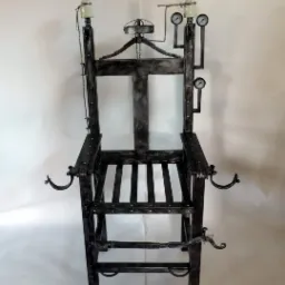 Metalowa konstrukcja krzesła z elementami dekoracyjnymi w stylu industrialnym, z widocznymi spawami i imitacją przyrządów pomiarowych, na neutralnym tle.